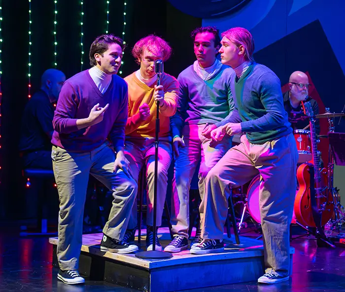 Four actors on stage signing.