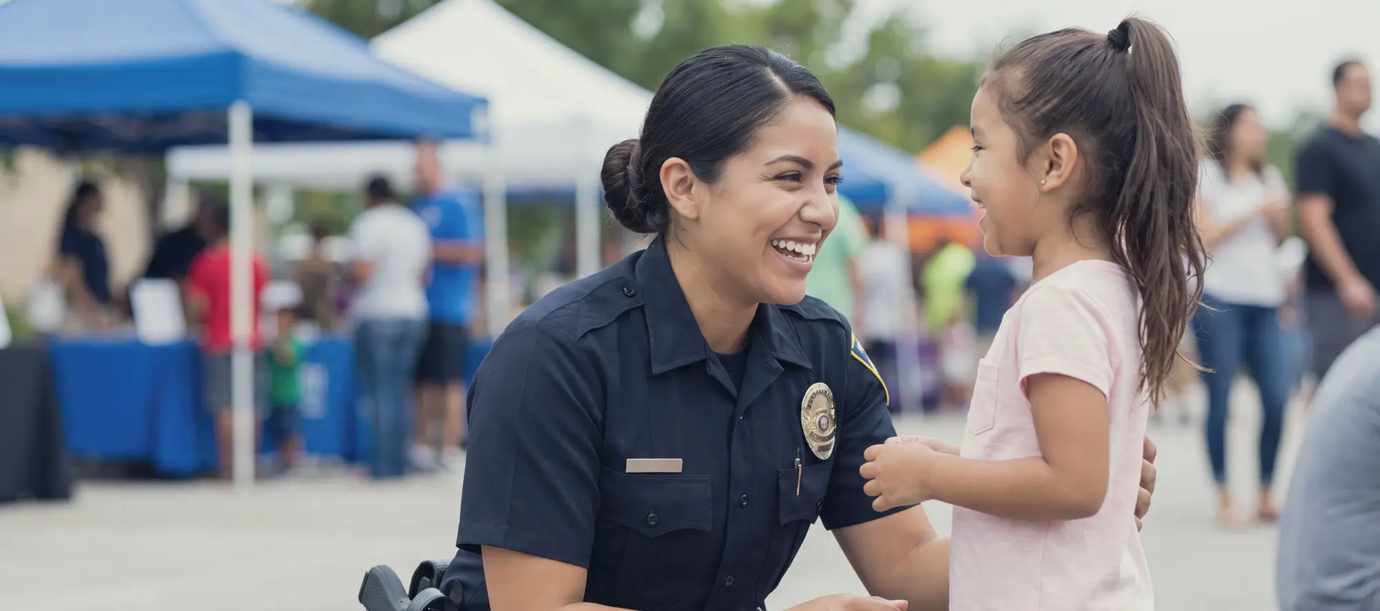Friendly police officer interacting with a young girl at an outdoor community event