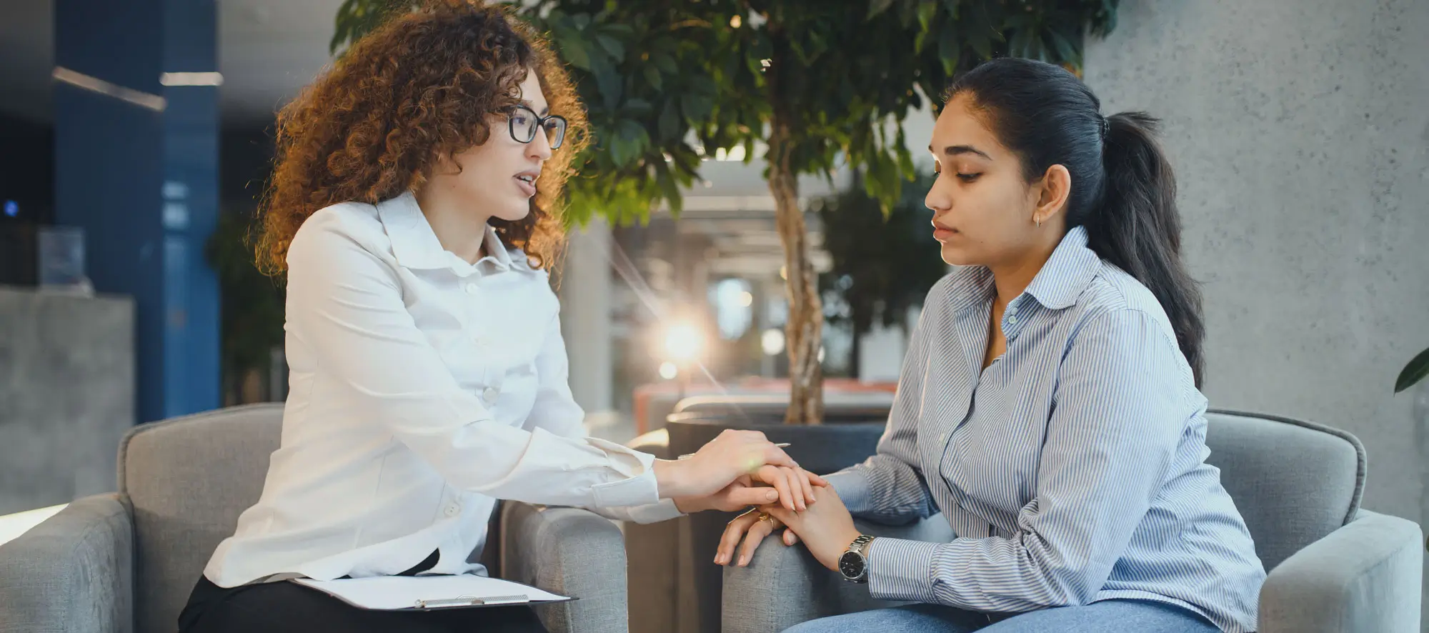 Psychologist providing empathy and support to indian woman patient during counseling session for mental health and well being.
