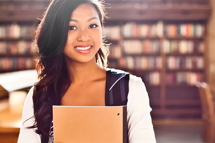 Student holding notebook in library.