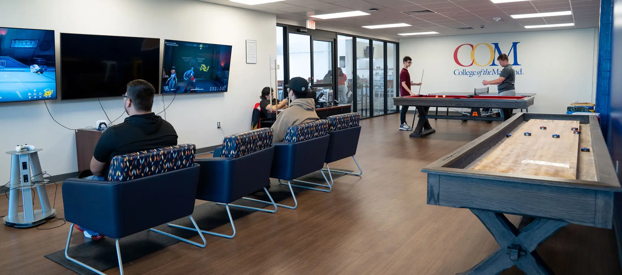 Students in rec room playing console games and pool.