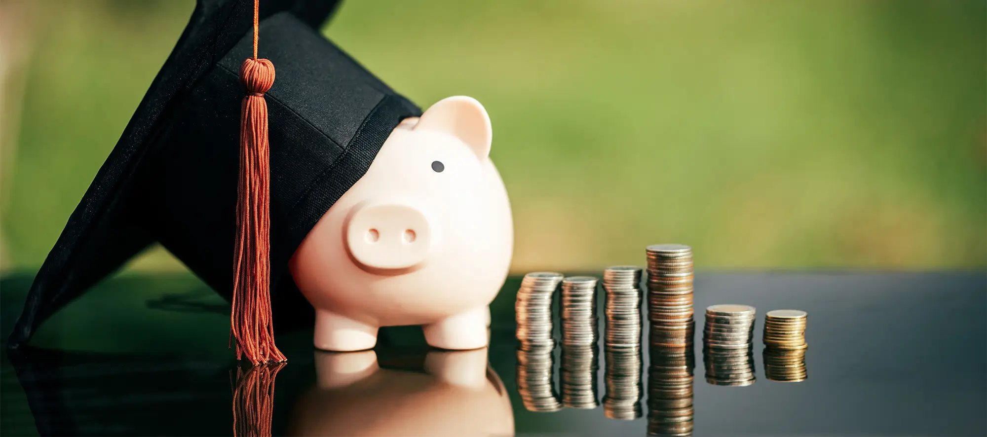 Piggy bank with graduation cap next to coins.