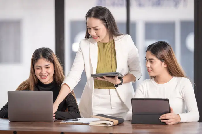 Advisor and two students in office using laptops and tablets