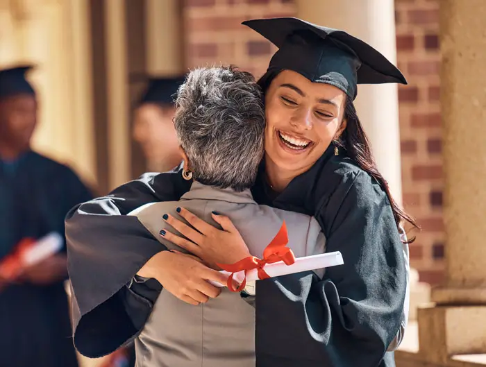 Graduate outside hugging family member