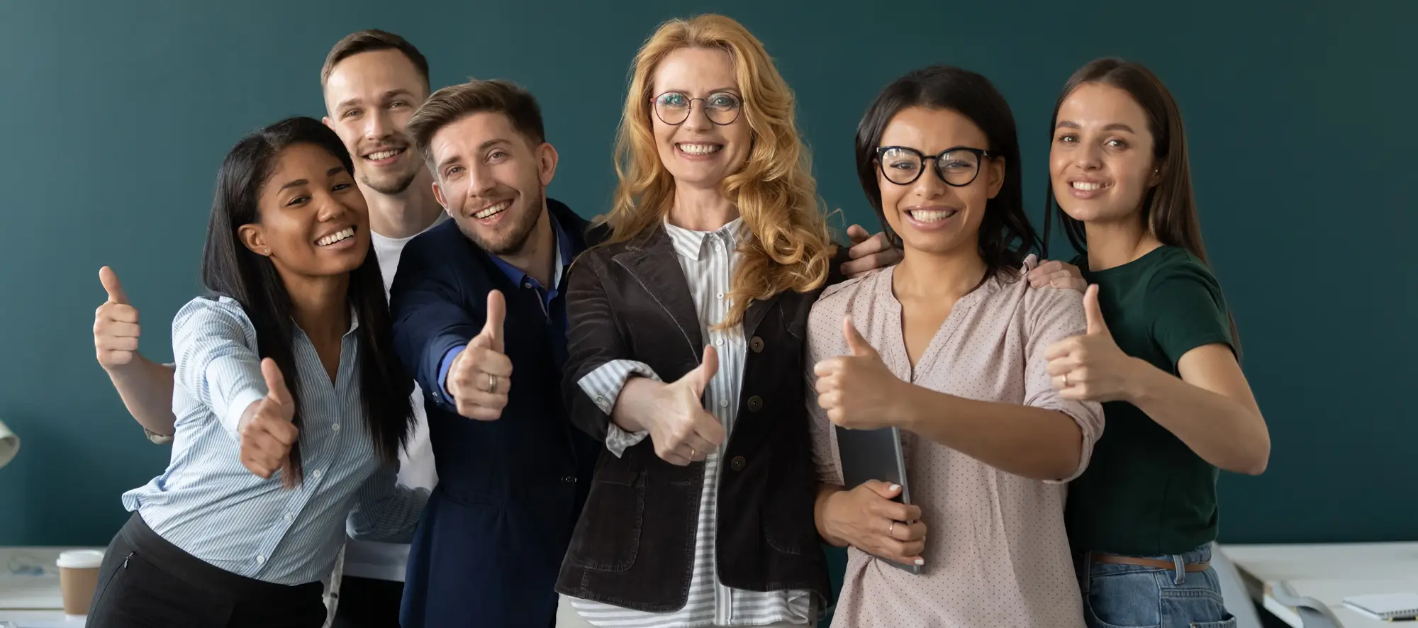 Group of students with teacher in all giving a thumbs up to the camera.