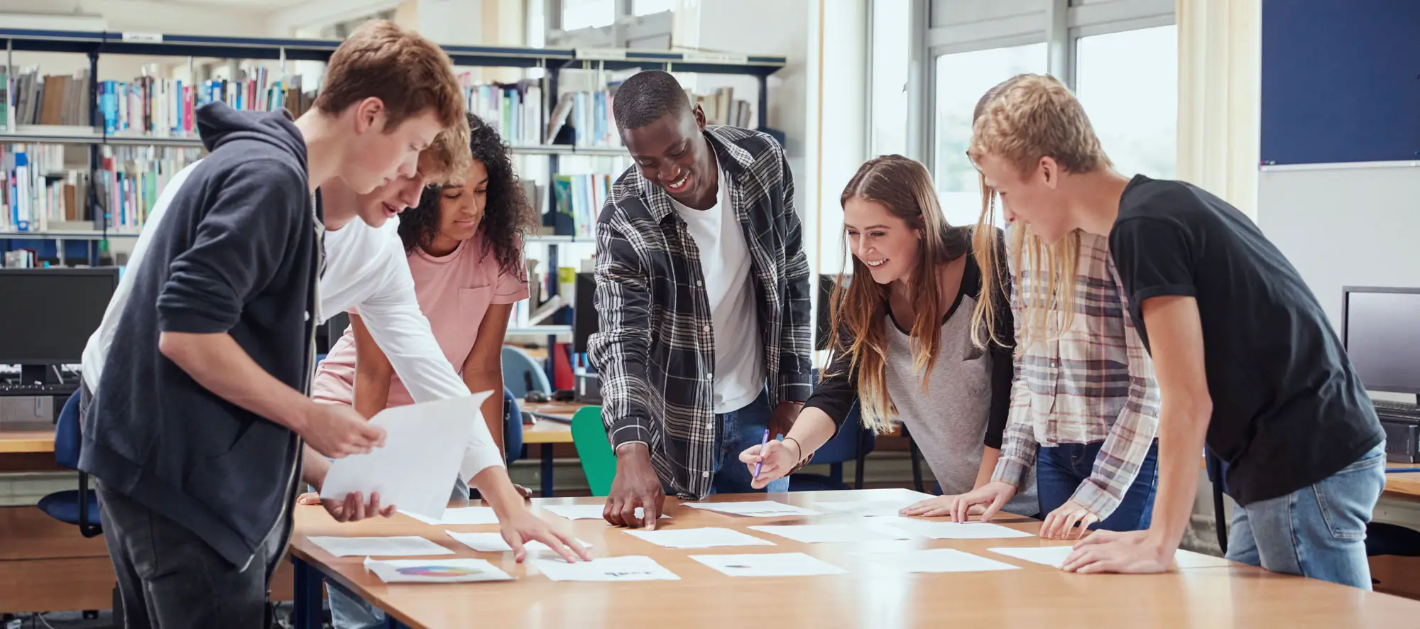 Group Of College Students Collaborating On Project In Library