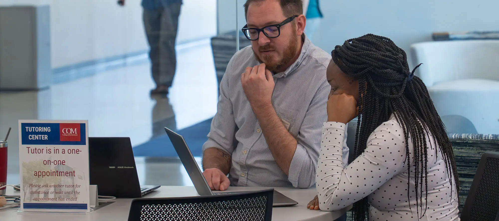 Instructor helping student at desk in the center.