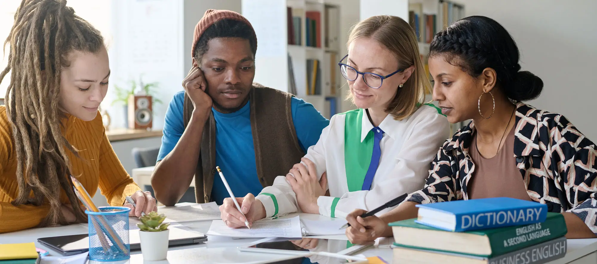 Young female teacher sitting at table with a group of students.
