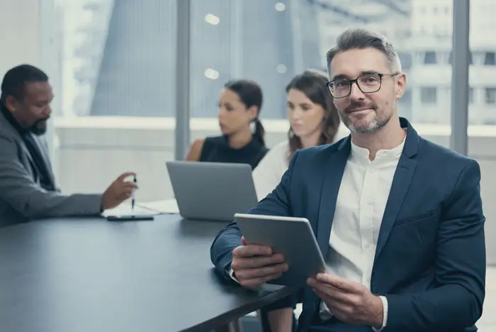 Group of professionals in a conference room next to a large window with city view.