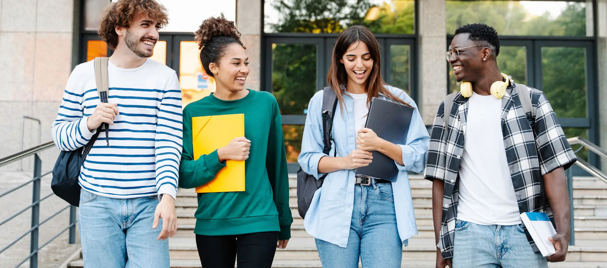 Happy students walking together on university campus, chatting and laughing outdoors after classes