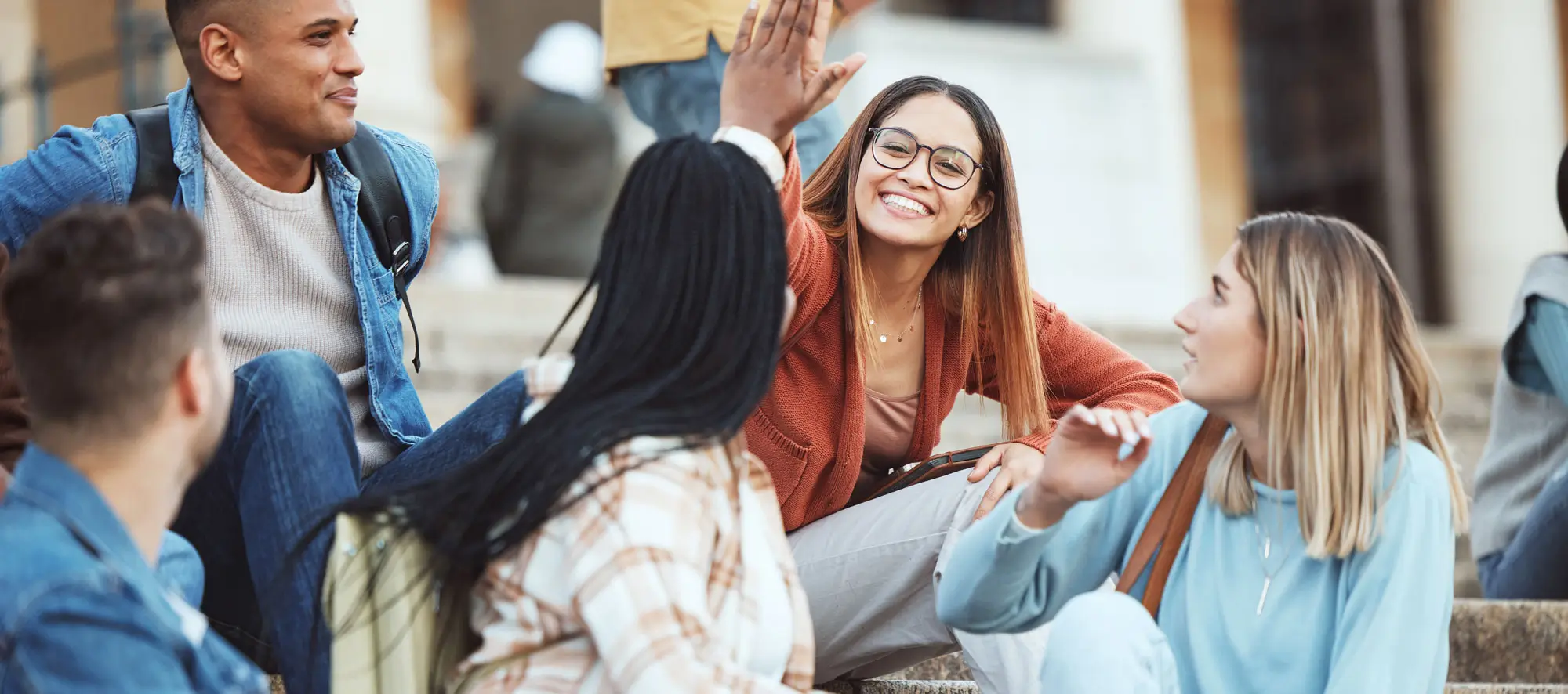 Students high five on university stairs.