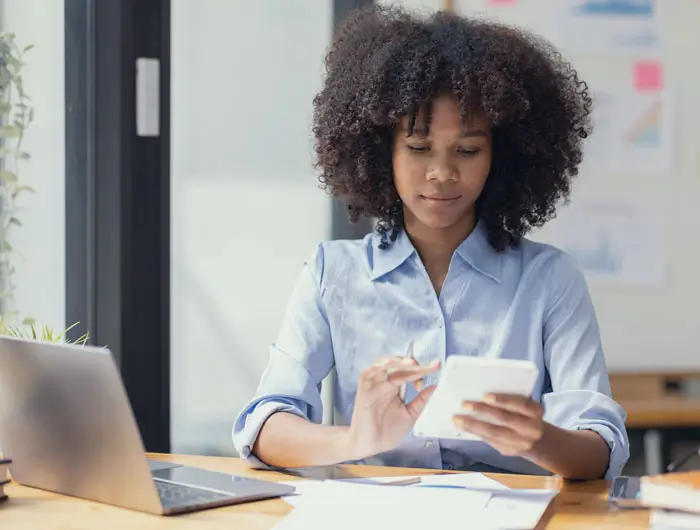 young female student using a calculator and laptop