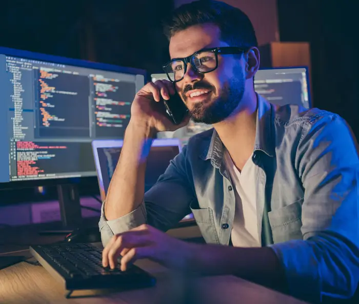 Young IT professional on phone typing at his computer